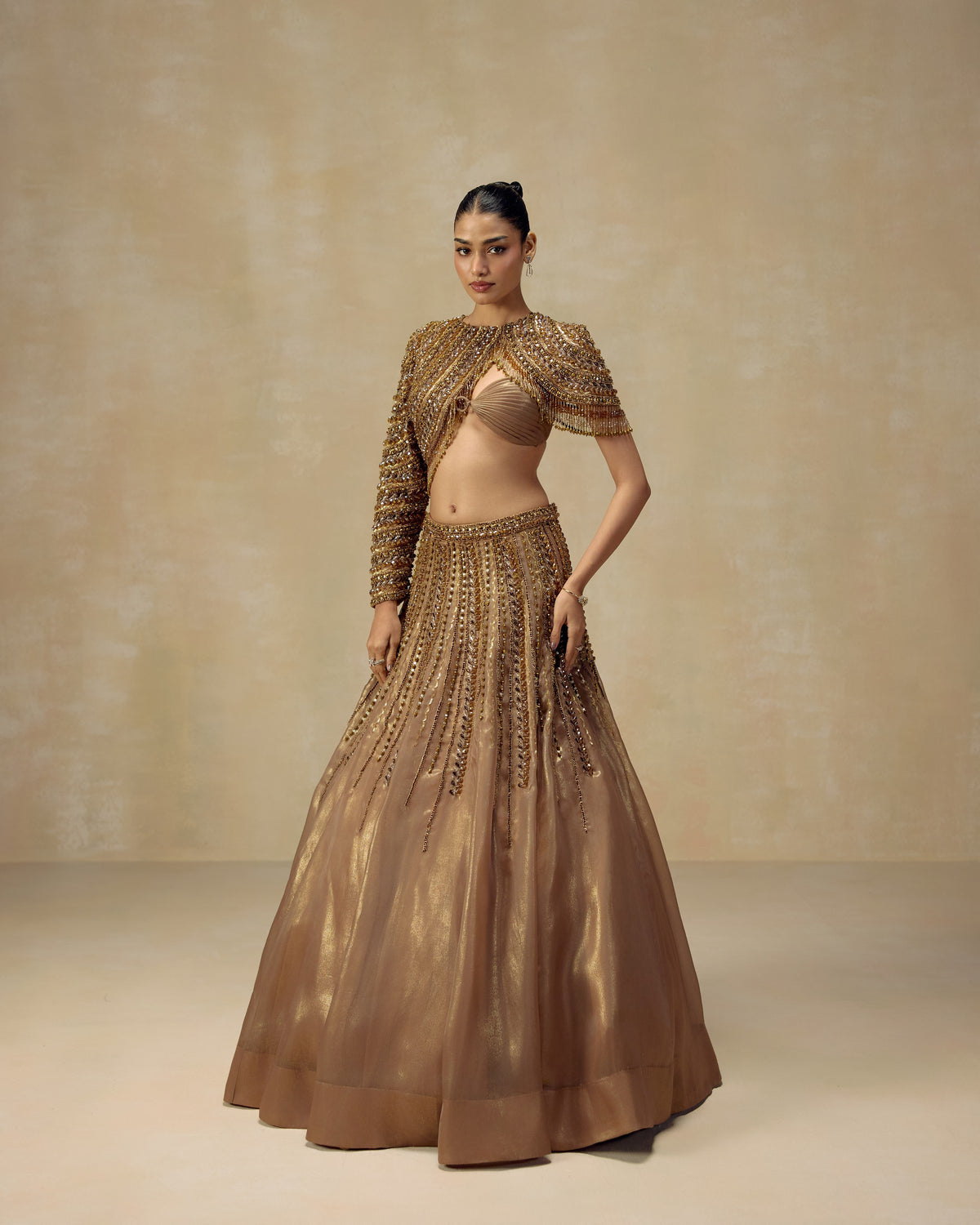 Gold luminous organza lehenga with fitted bustier and cropped cape-sleeve jacket hand-set with crystals — RINESSA